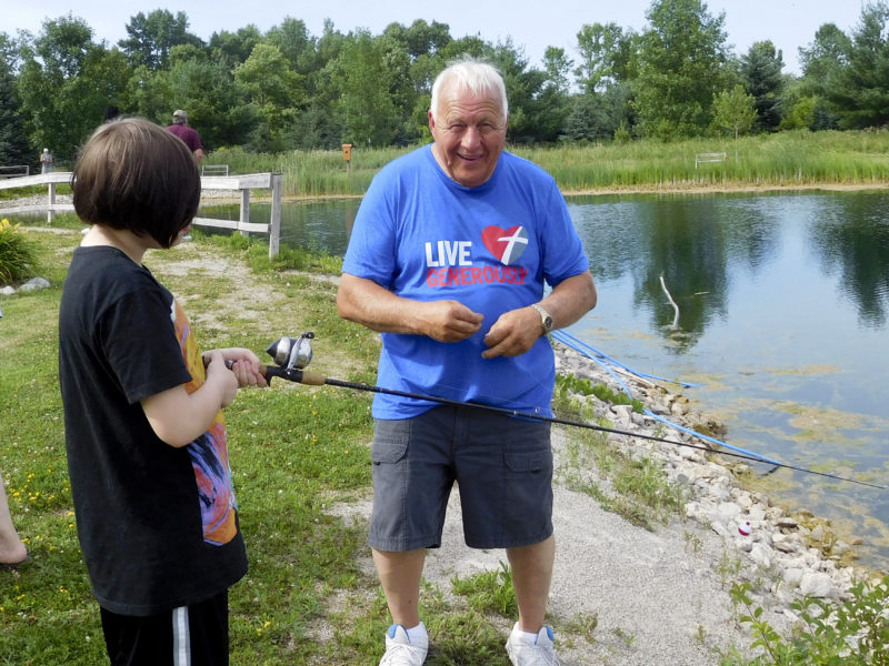 Pat Hill helping a young lady fish